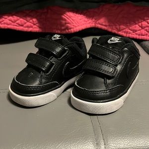 Black leather Nikes with white soles and Velcro closure